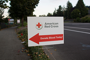 Red and white sign with red arrow for American Red Cross blood drive