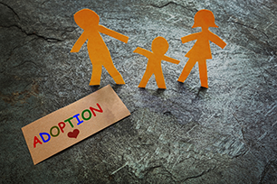 Paper figures for parents and child with words of adoption